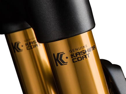 Close-up of bicycle suspension stanchions featuring the gold-colored Genuine Kashima Coat lubricating anodizing finish and logo.