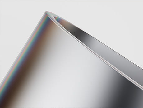 Macro view of a high-precision metal surface showing rainbow interference colors from a smooth Kashima Coat finish.